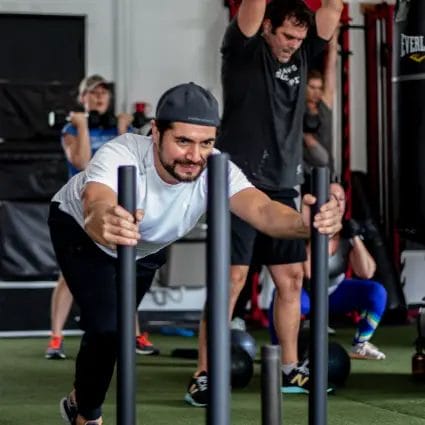 Athletes pushing sled during strength workout at Real Fitness gym